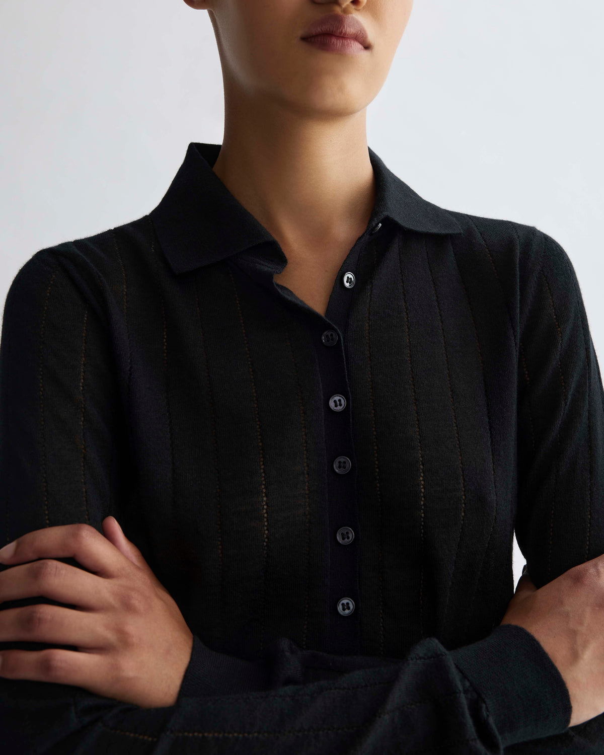Luxury black fine gauge knit long sleeve polo shirt with subtle vertical textured stripes and button placket