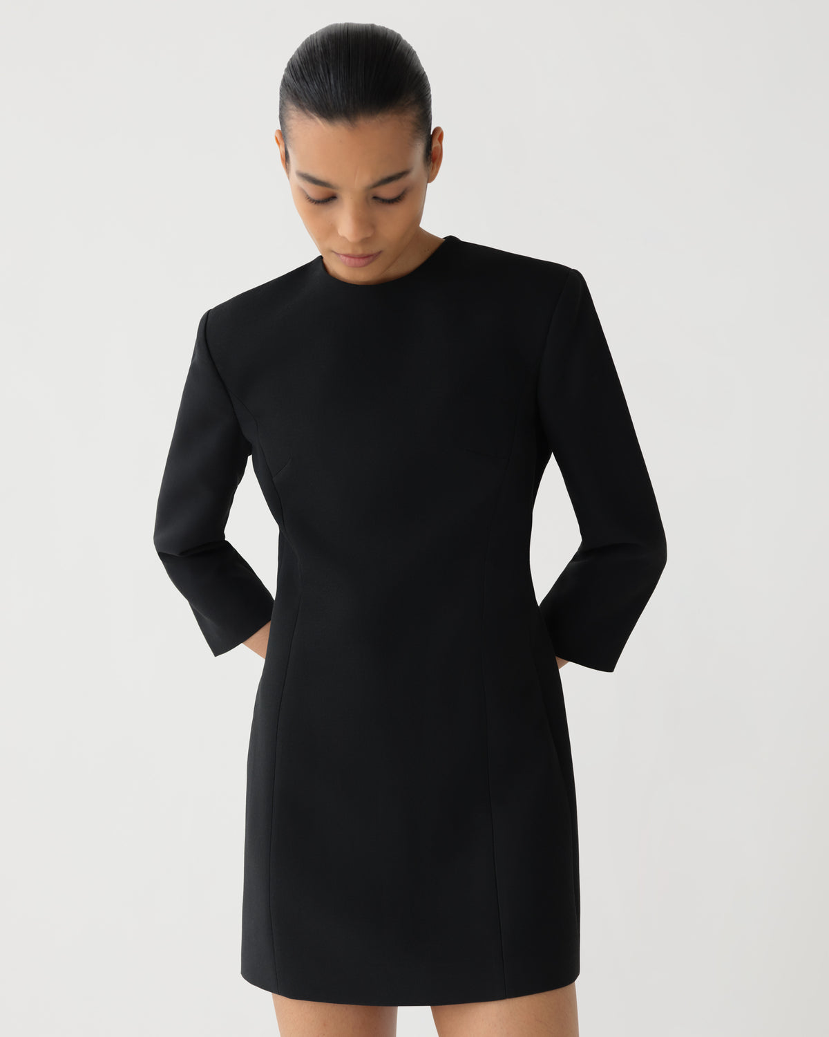 Black tailored mini dress women's luxury style with structured shoulders crew neck long sleeves and sleek fit on model
