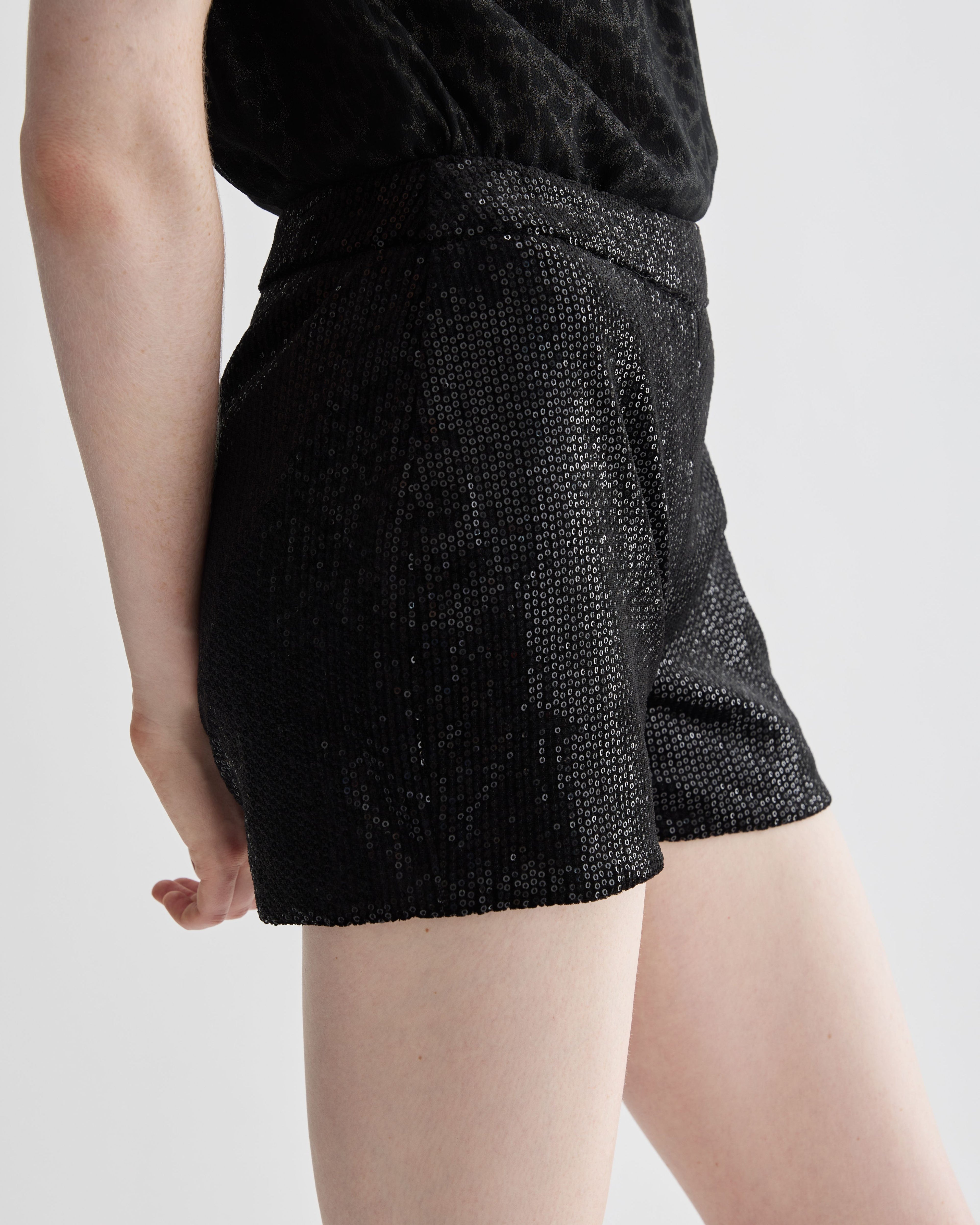 Black Helena Shorts in stretch sequin by Veronica De Piante, close-up of shiny, fitted bottoms with sequin detail.