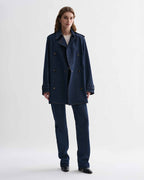 Blue Charlotte denim trench coat by Veronica De Piante hanging on a clothing rack with front view.