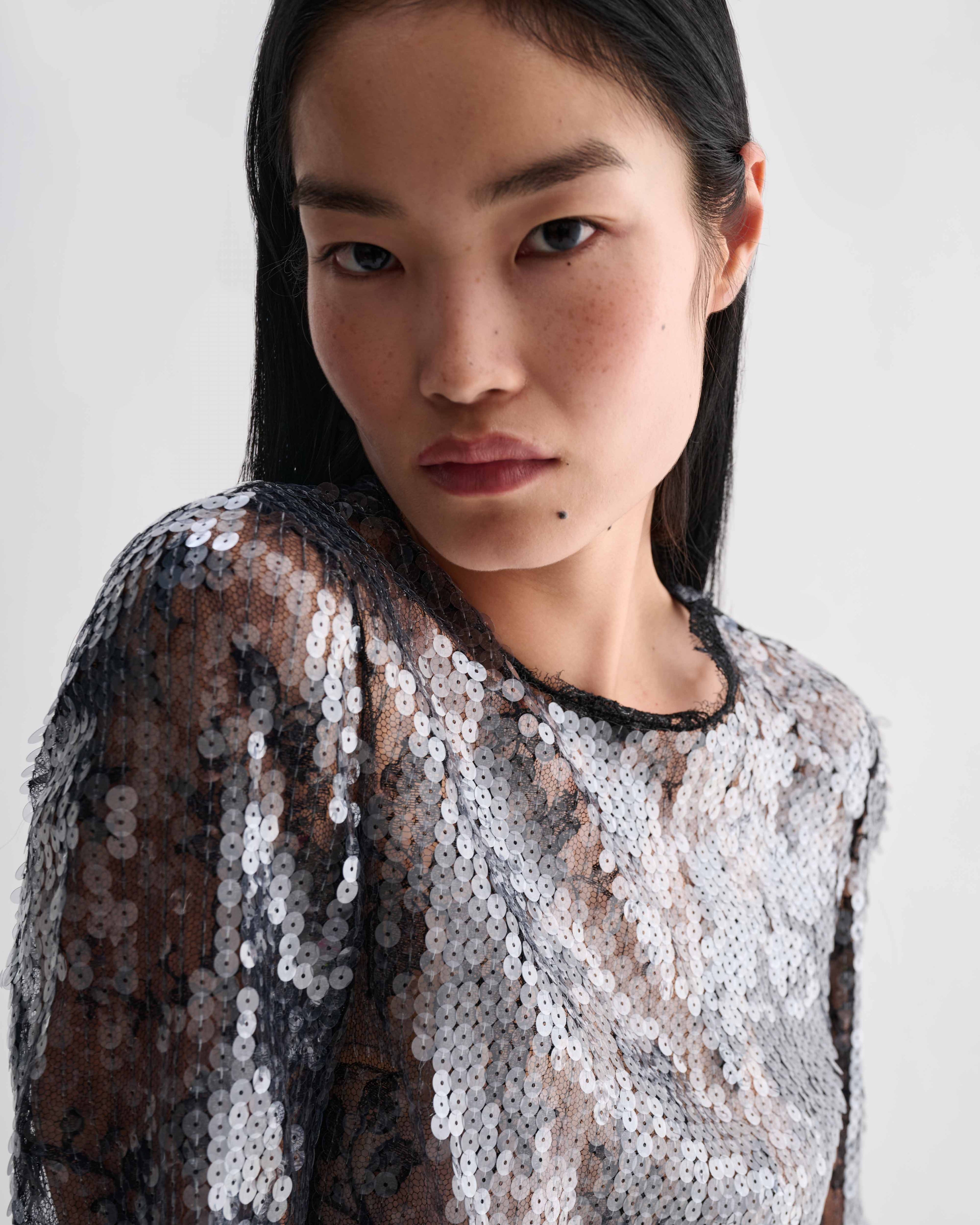 Dalia Top, black lace sequin crewneck top. Model wearing shimmering luxury evening top with dimensional texture