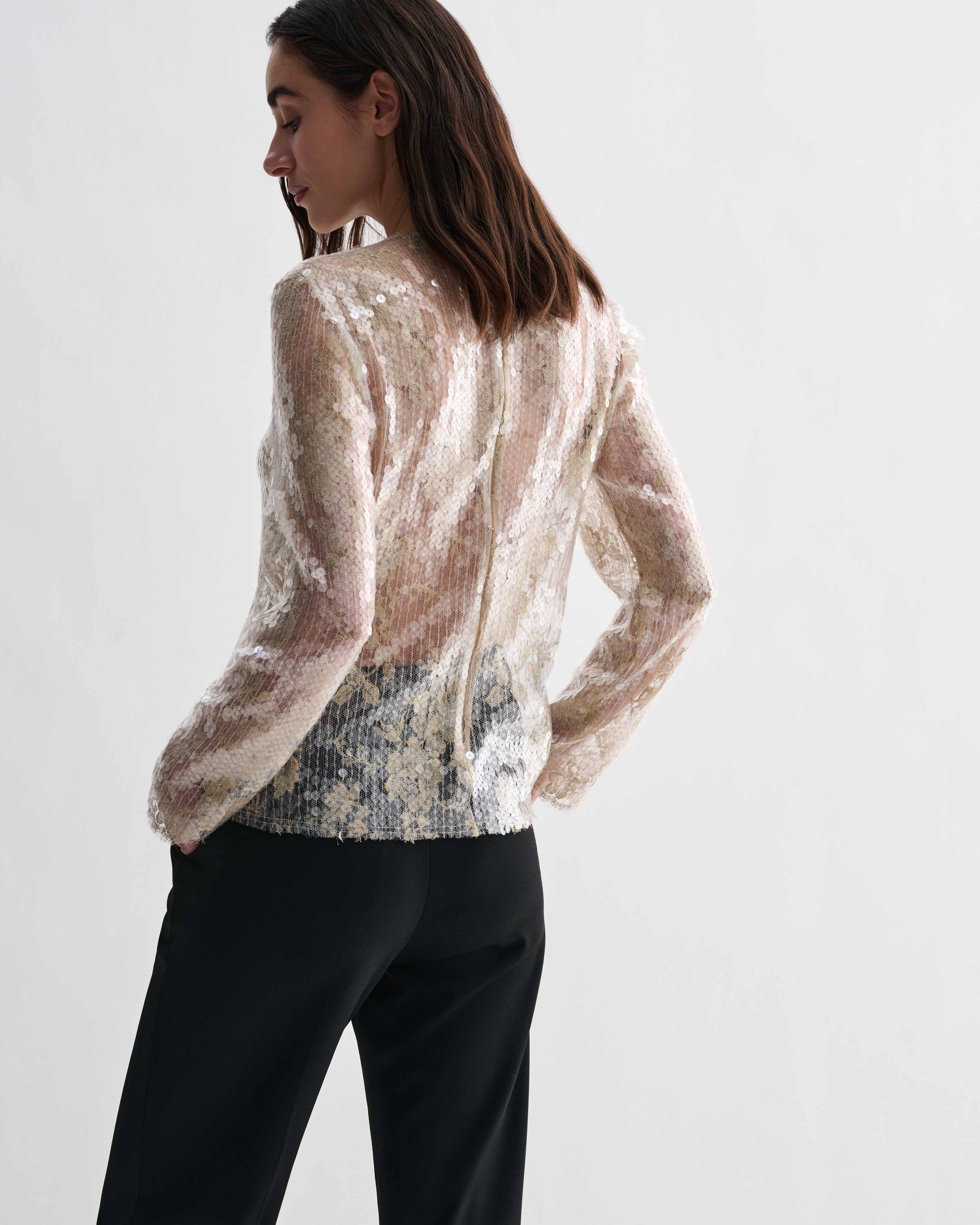 Gold Dalia Top in lace sequins. Sheer, long-sleeved luxury top with intricate texture and shimmer on model