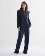 Model wears Dylan Trouser, straight-leg tailored pure wool trousers in petrol blue, paired with matching Roman suit jacket