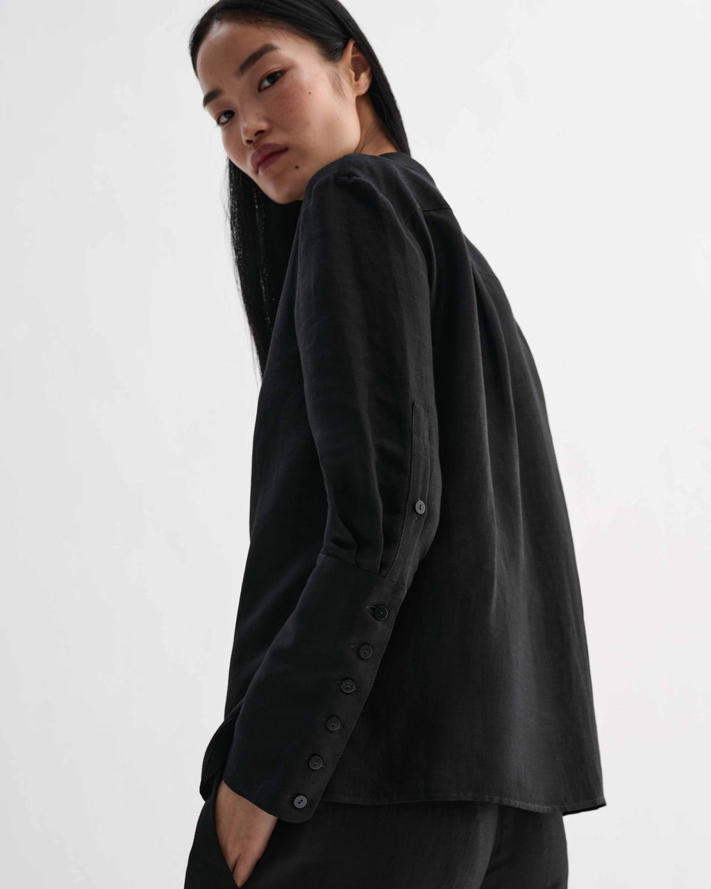 Black Livia linen shirt by Veronica De Piante, shown on a hanger with a relaxed fit and natural fabric texture.