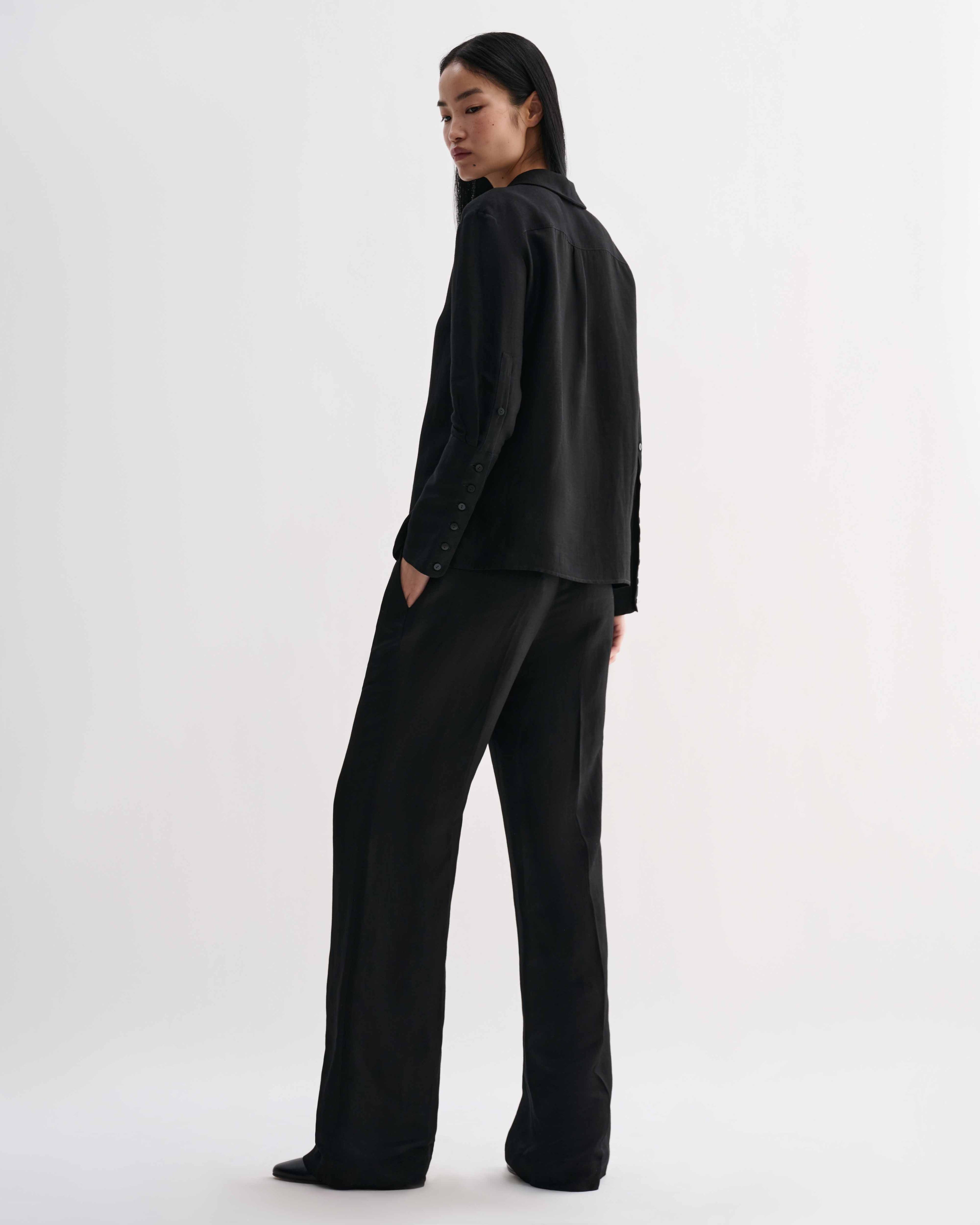 Black Livia linen shirt by Veronica De Piante, featuring a relaxed fit and stylish design, displayed on a hanger.
