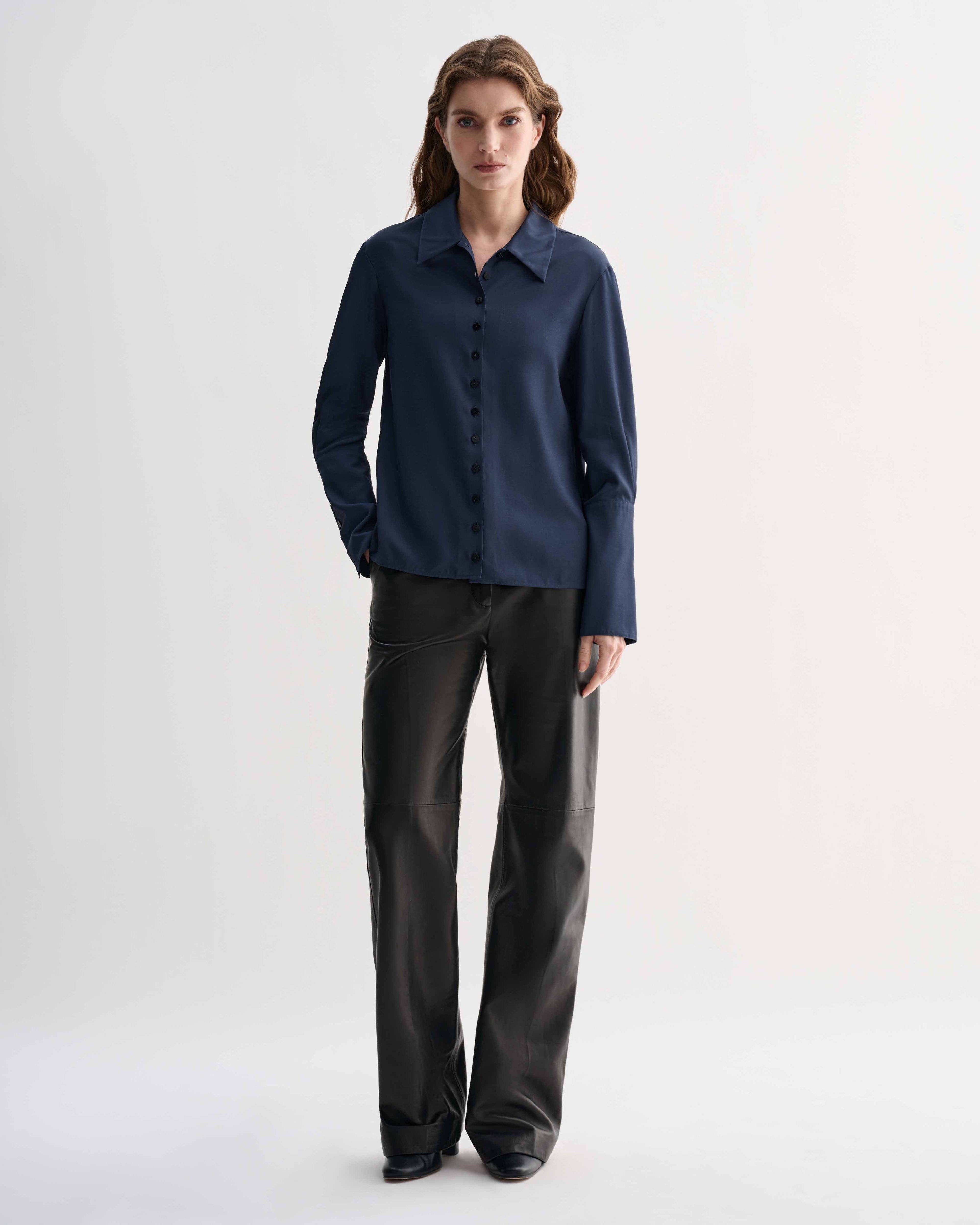 Female model wearing Livia Shirt in Petrol Blue silk, a feminine button-down shirt with elongated cuffs & delicate buttons