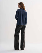 Livia Silk Shirt, Petrol Blue, back view on model. Feminine long-sleeve button-up top with elongated cuffs
