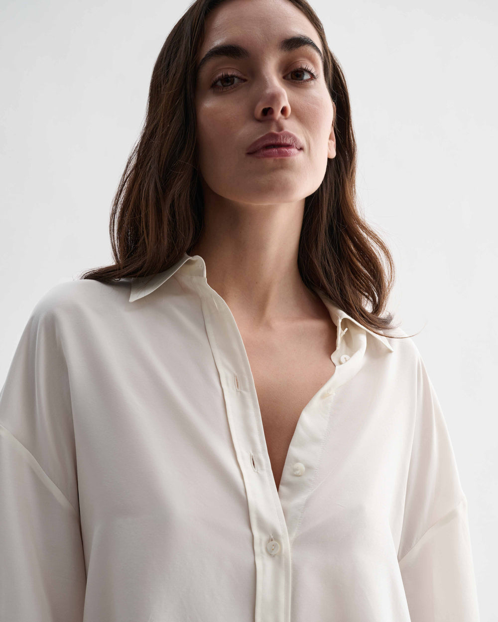 Off-white silk Maren shirt by Veronica De Piante, featuring a relaxed fit and elegant design, displayed on a hanger.