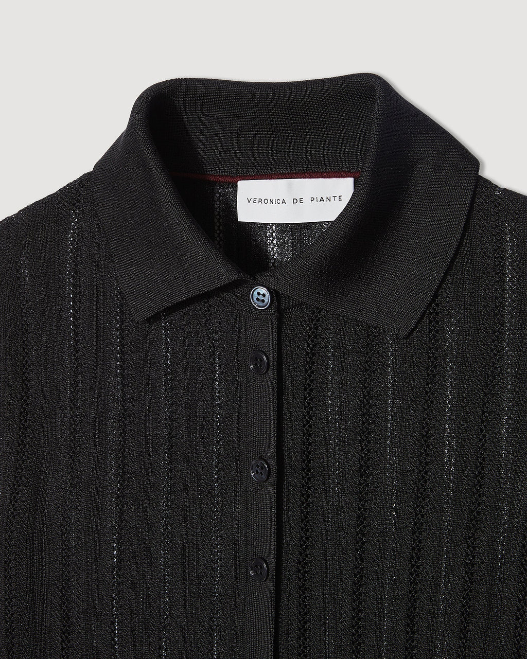 Black Lydia Polo in silk crepe knitwear by SALE, featuring a classic polo collar and smooth fabric texture.