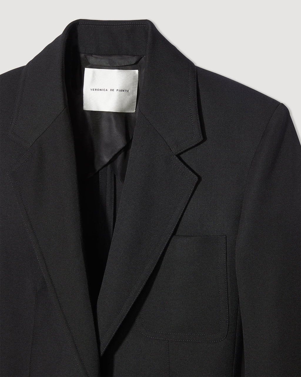 Black Faye Wool Jacket by Veronica de Piante, stylish coat with a tailored fit and classic design, displayed on a hanger.
