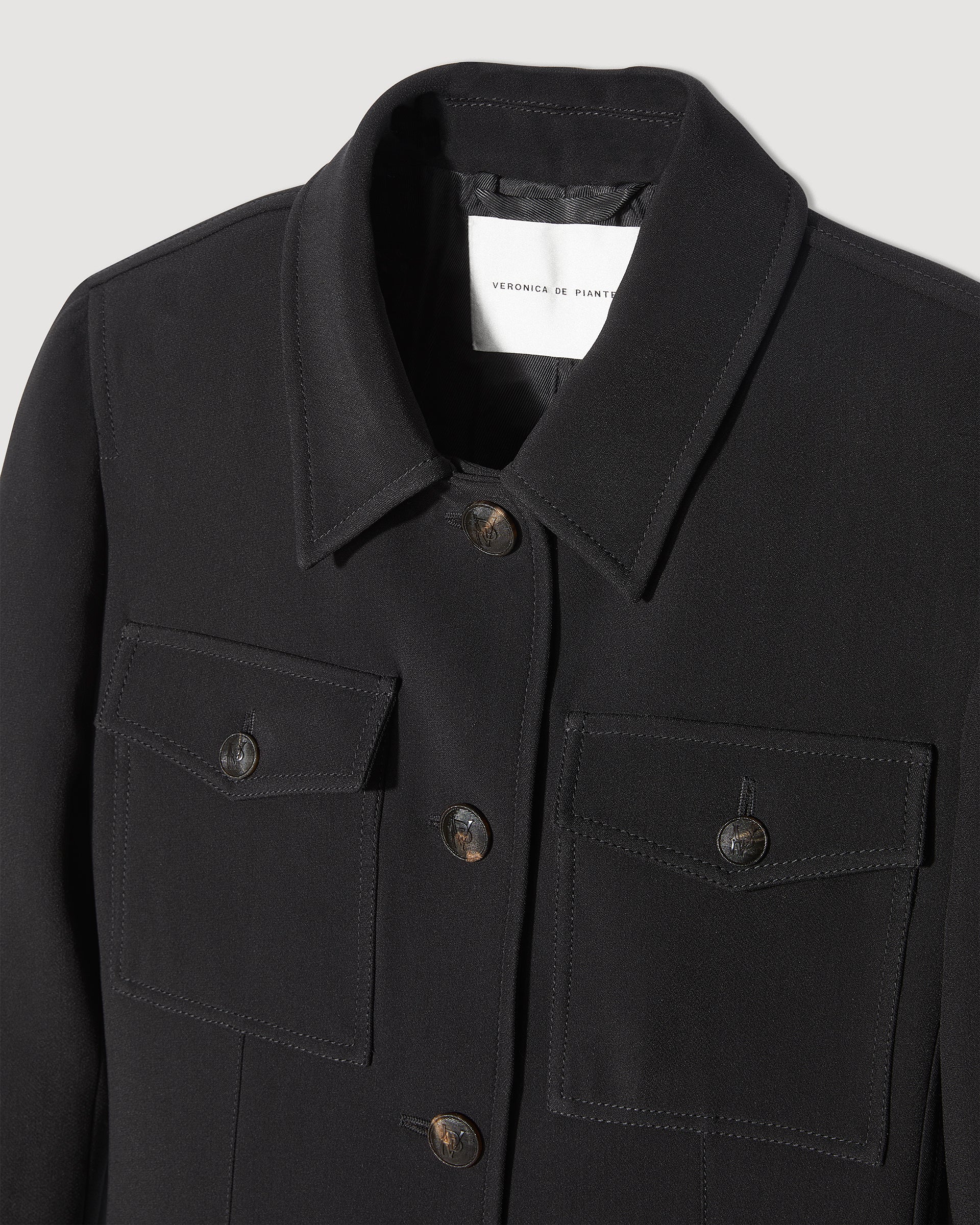 Black Alma jacket in viscose crepe by Veronica De Piante, showcasing its sleek coat design and textured fabric.