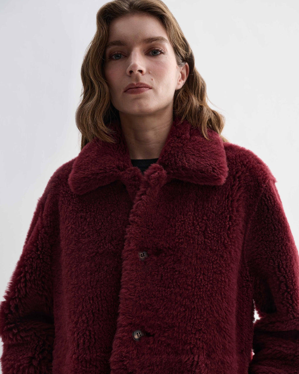 Romy Coat, bordeaux red double-faced shearling, generous volume, worn by model with visible buttons