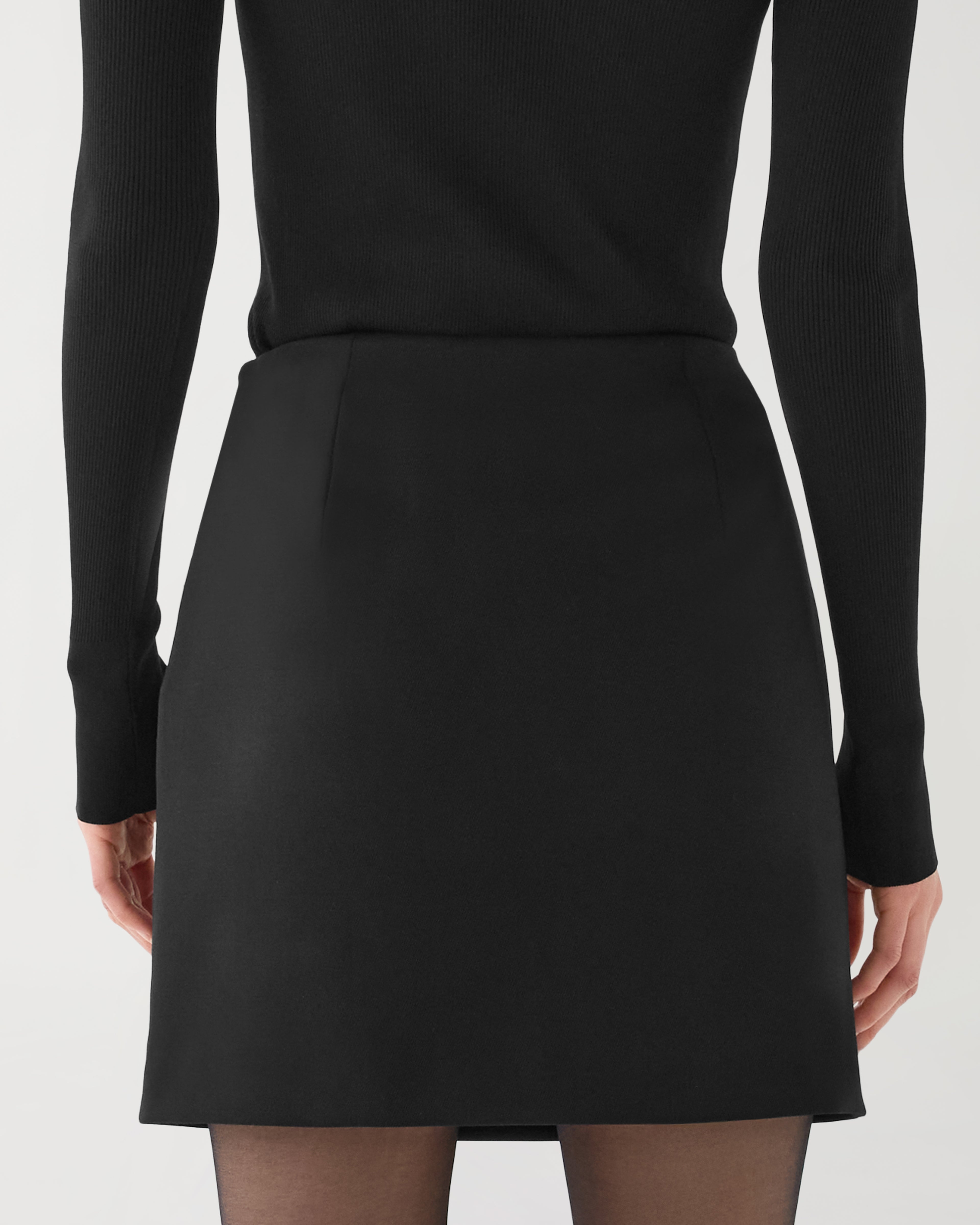 Black Sabine skirt in stretch wool twill by Veronica De Piante, shown laid flat to highlight its tailored design and fabric texture.
