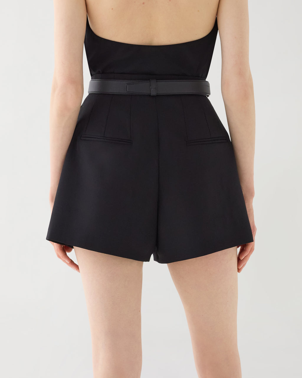 Black Tilly high-waisted Grain de Poudre wool tailored shorts, visible back darts and welt pockets, worn by model from behind