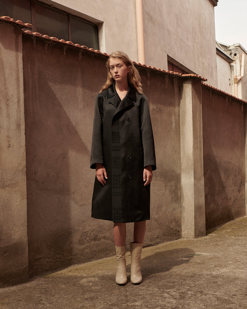 Luxury women's charcoal double-breasted overcoat, wide lapels, relaxed knee-length fit, subtle geometric embroidery