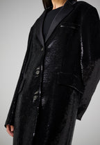 Black flat sequin Arlo coat by SALE, showcasing a sleek design and elegant texture in a stylish outdoor setting.